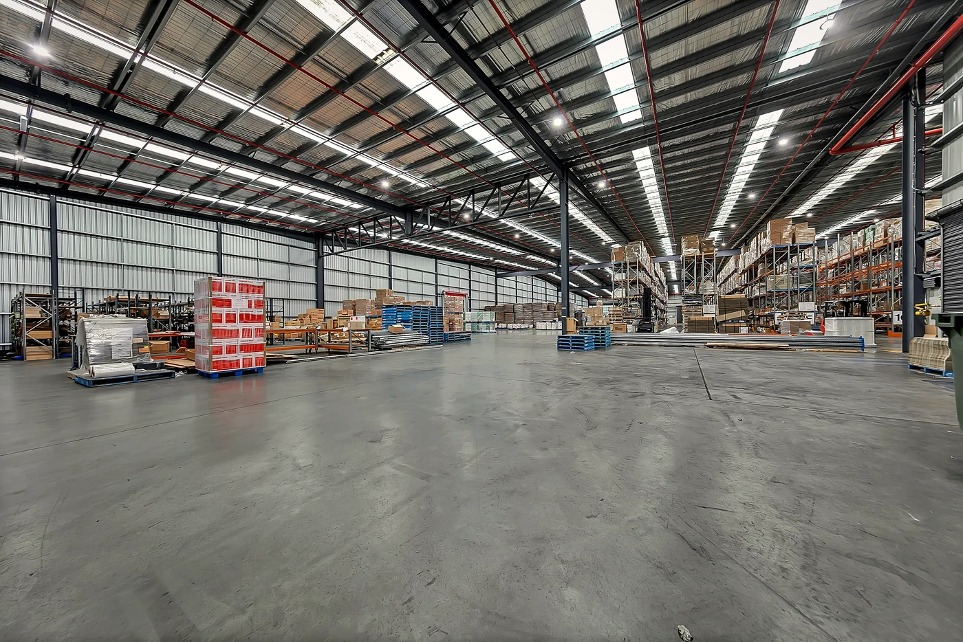 A clear-span working warehouse with high-bay racking and polished concrete floor, photographed by Sixth Vision