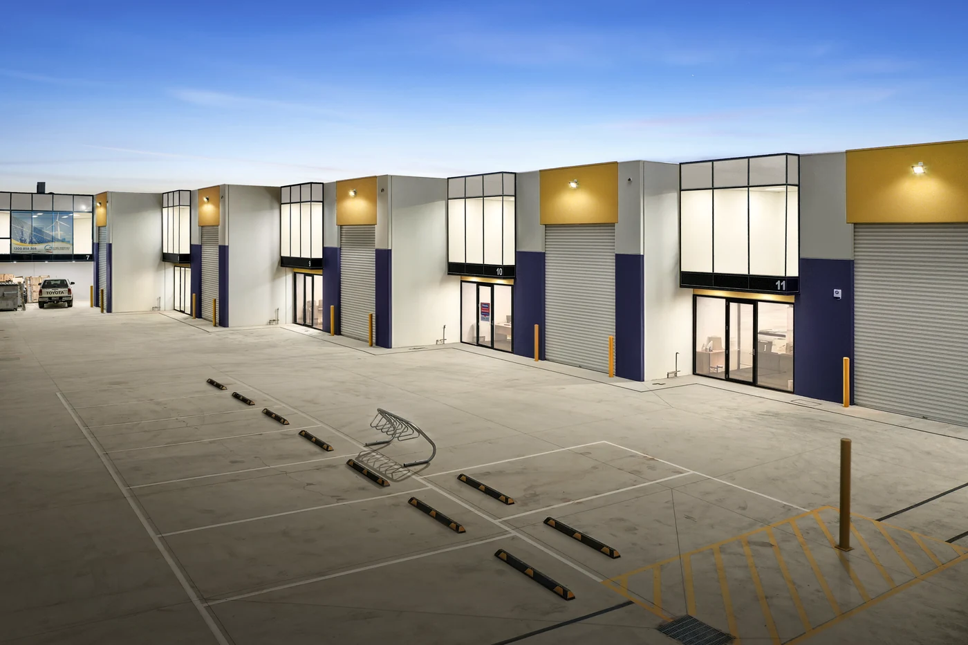 Commercial real estate photography Melbourne — a row of new industrial units with glass frontages and roller doors, ready to lease