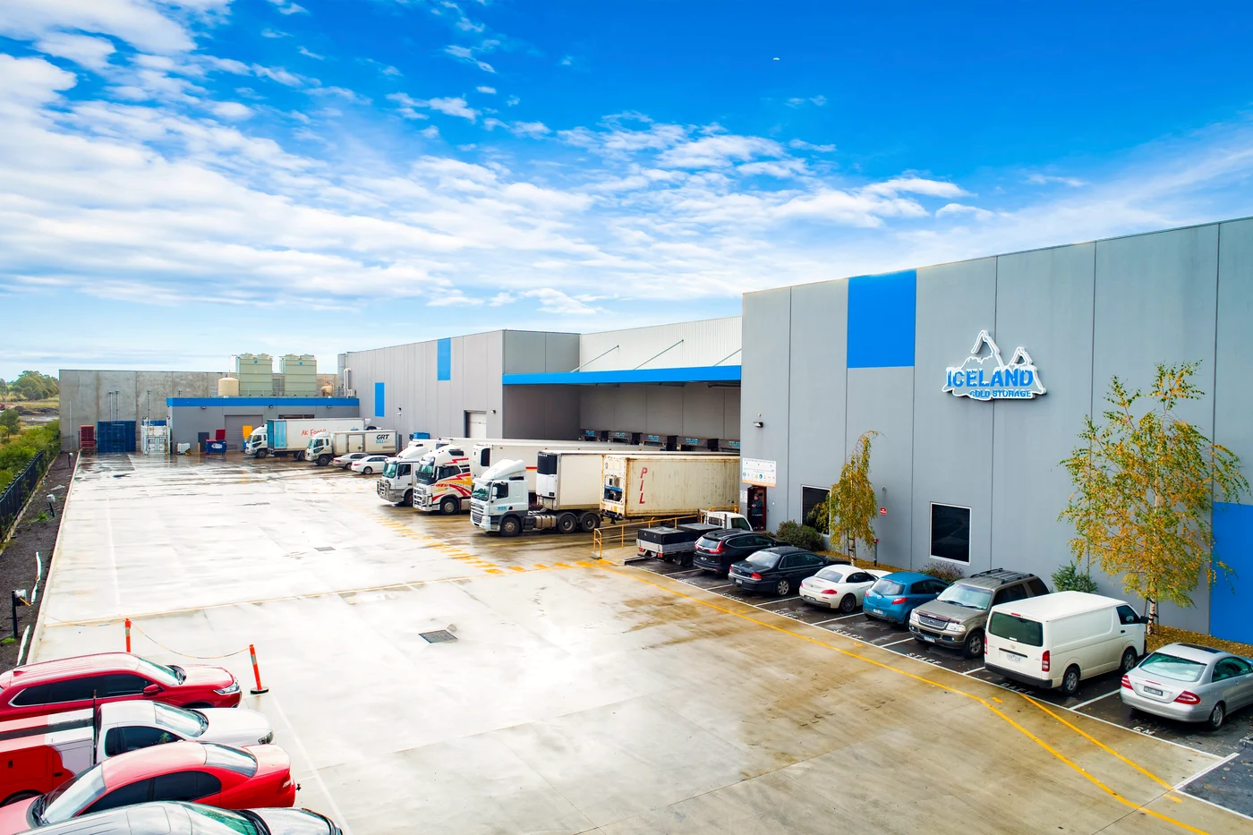 Commercial real estate photographer Melbourne — cold-storage distribution facility under open sky with refrigerated trucks at the loading docks