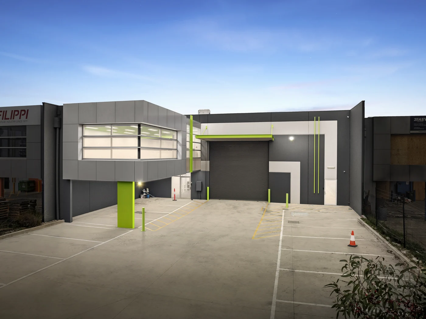Commercial real estate photographer Melbourne — office-and-warehouse unit photographed at dusk with lit facade and green architectural accents