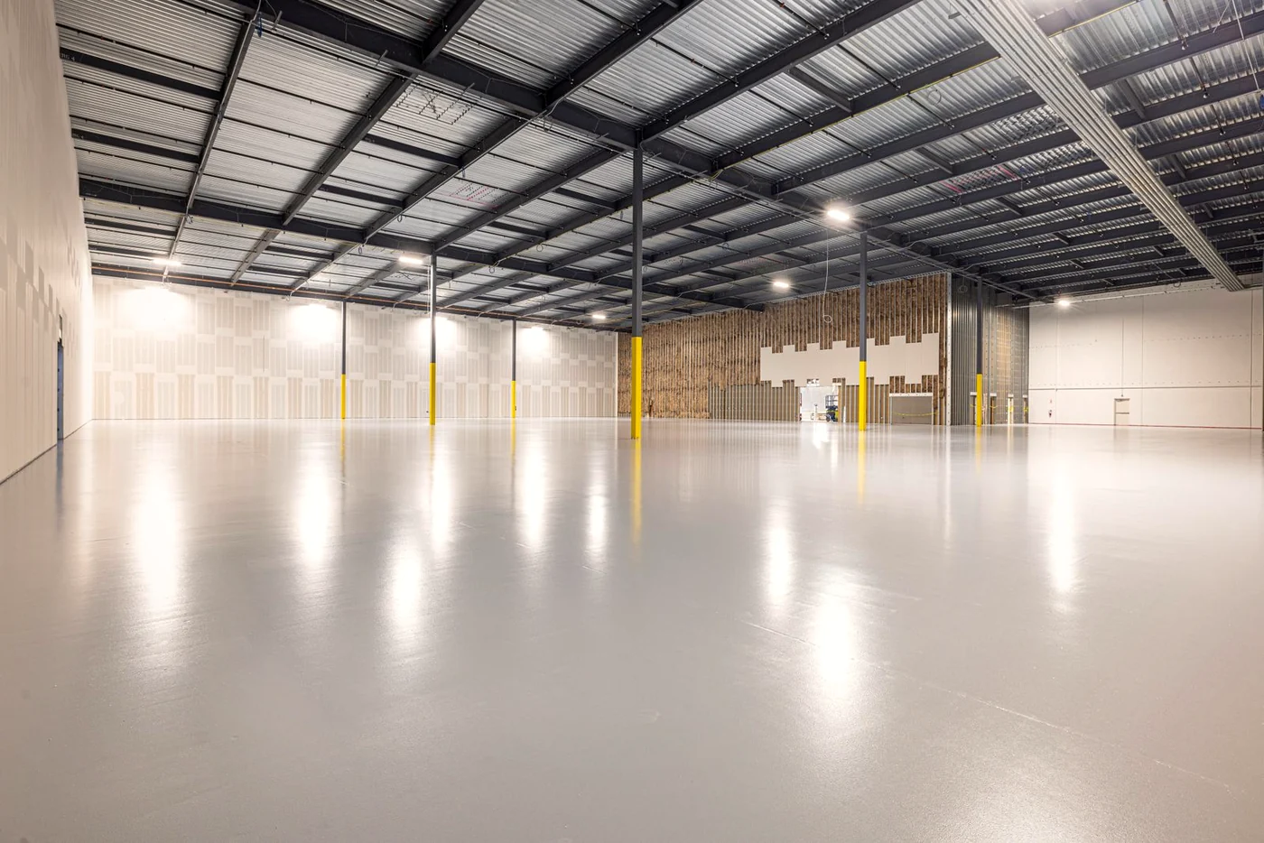 Commercial industrial real estate photography Melbourne — a vast empty warehouse floor lit through skylights, shown at leasing scale